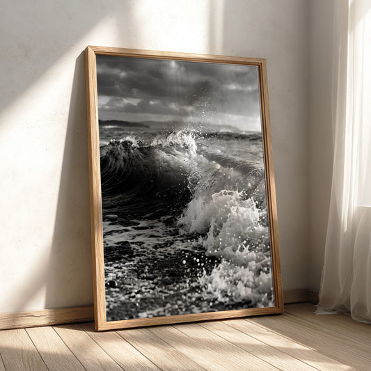 Black and white poster of a breaking wave on rocky beach with splashing water and moody sky