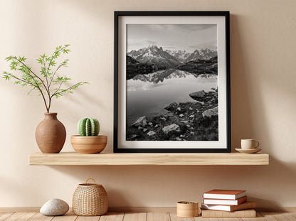 Black and white photographic wall decor showing alpine lake reflecting jagged mountain peaks and rocky shore