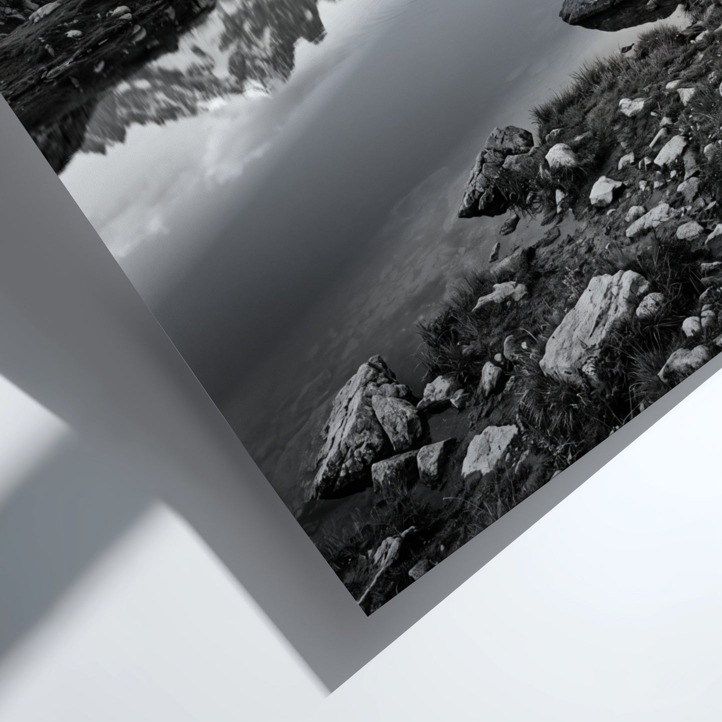 Black and white photographic wall decor showing alpine lake reflecting jagged mountain peaks and rocky shore