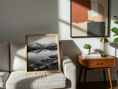 Black and white photographic wall decor showing alpine lake reflecting jagged mountain peaks and rocky shore