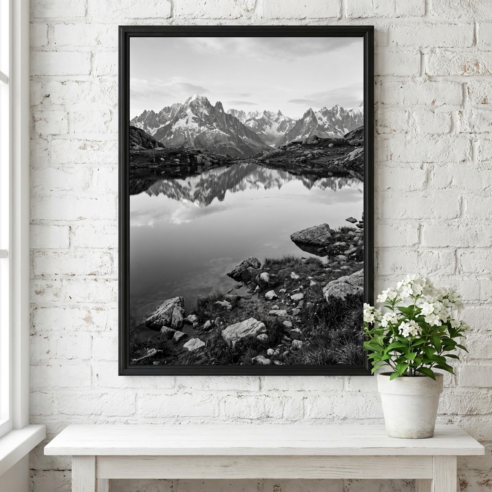 Black and white photographic wall decor showing alpine lake reflecting jagged mountain peaks and rocky shore