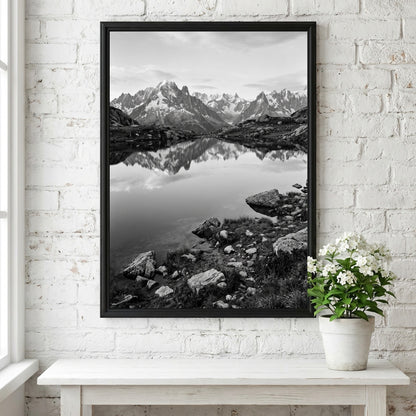 Black and white photographic wall decor showing alpine lake reflecting jagged mountain peaks and rocky shore