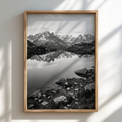 Black and white photographic wall decor showing alpine lake reflecting jagged mountain peaks and rocky shore
