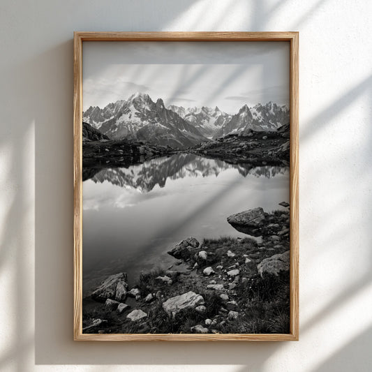 Black and white photographic wall decor showing alpine lake reflecting jagged mountain peaks and rocky shore