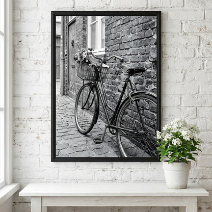 Black and white poster of vintage bicycle leaning against textured brick wall on cobblestone street