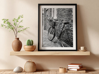 Black and white poster of vintage bicycle leaning against textured brick wall on cobblestone street