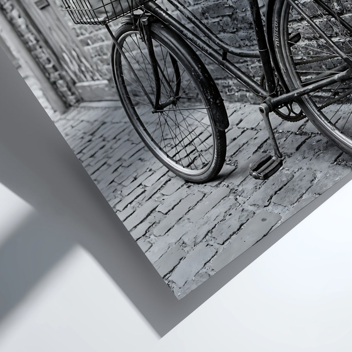 Black and white poster of vintage bicycle leaning against textured brick wall on cobblestone street