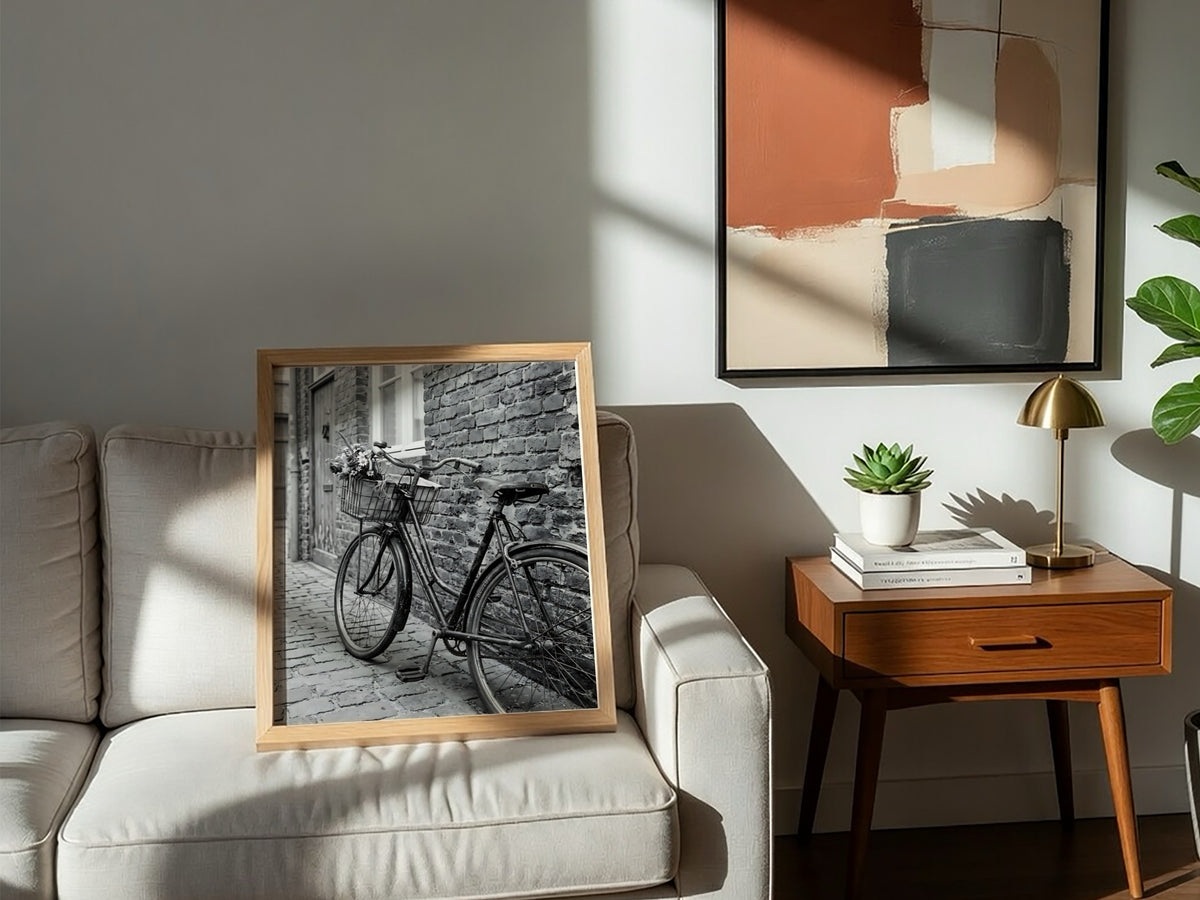 Black and white poster of vintage bicycle leaning against textured brick wall on cobblestone street