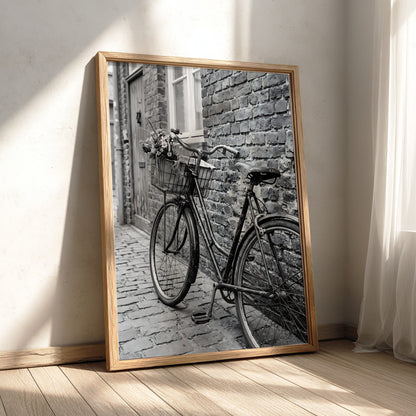 Black and white poster of vintage bicycle leaning against textured brick wall on cobblestone street