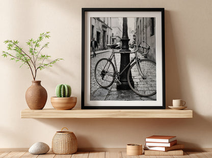 Black and white wall decor featuring vintage bicycle parked against ornate lamppost on cobblestone street