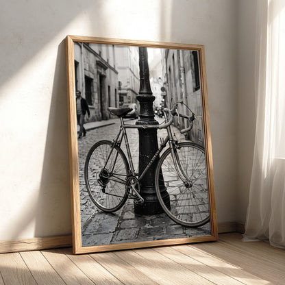 Black and white wall decor featuring vintage bicycle parked against ornate lamppost on cobblestone street