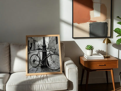 Black and white wall decor featuring vintage bicycle parked against ornate lamppost on cobblestone street