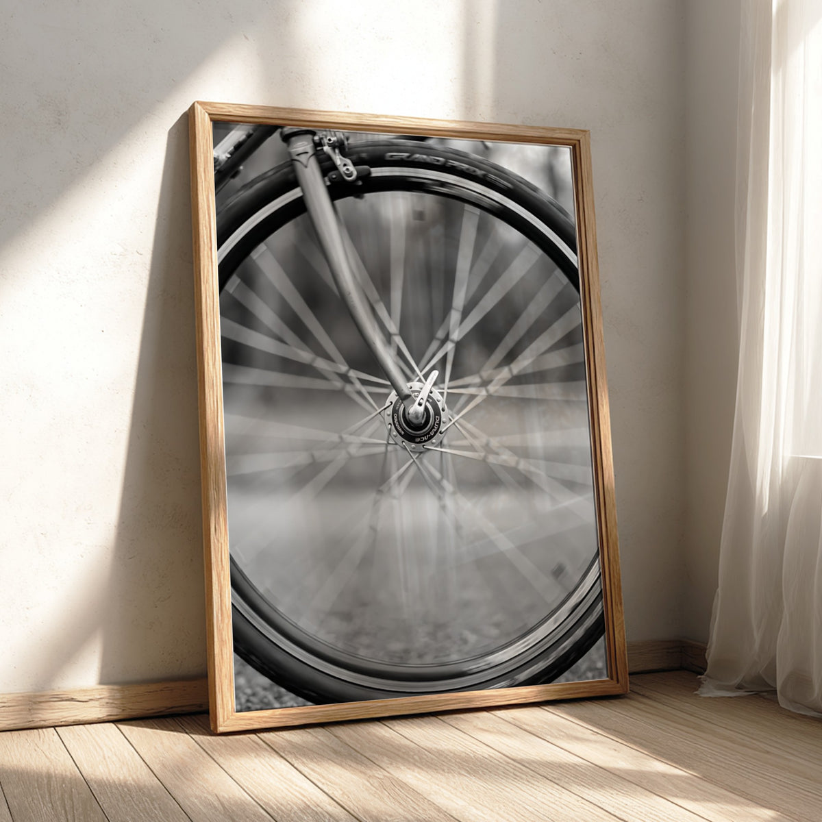 Black and white wall art of bicycle wheel in motion with blurred spokes and sharp mechanical details