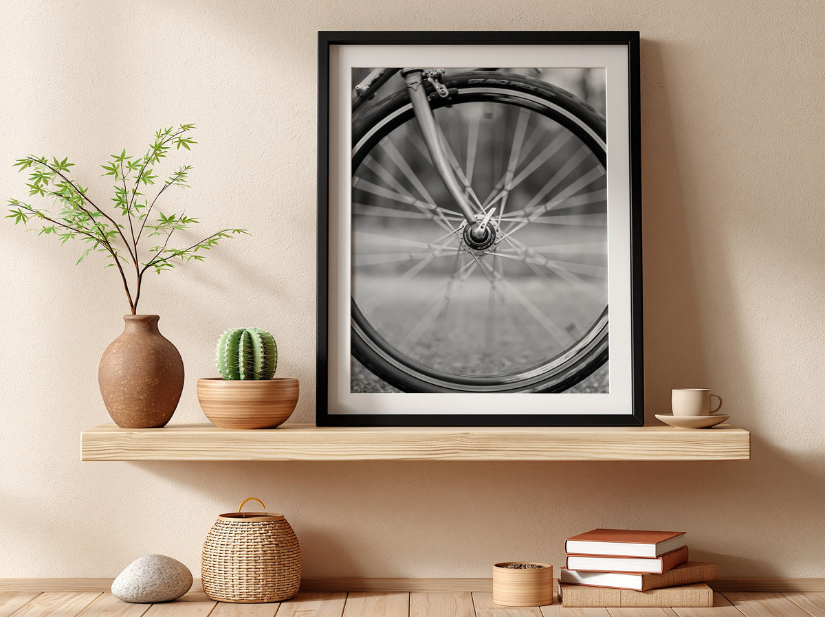 Black and white wall art of bicycle wheel in motion with blurred spokes and sharp mechanical details
