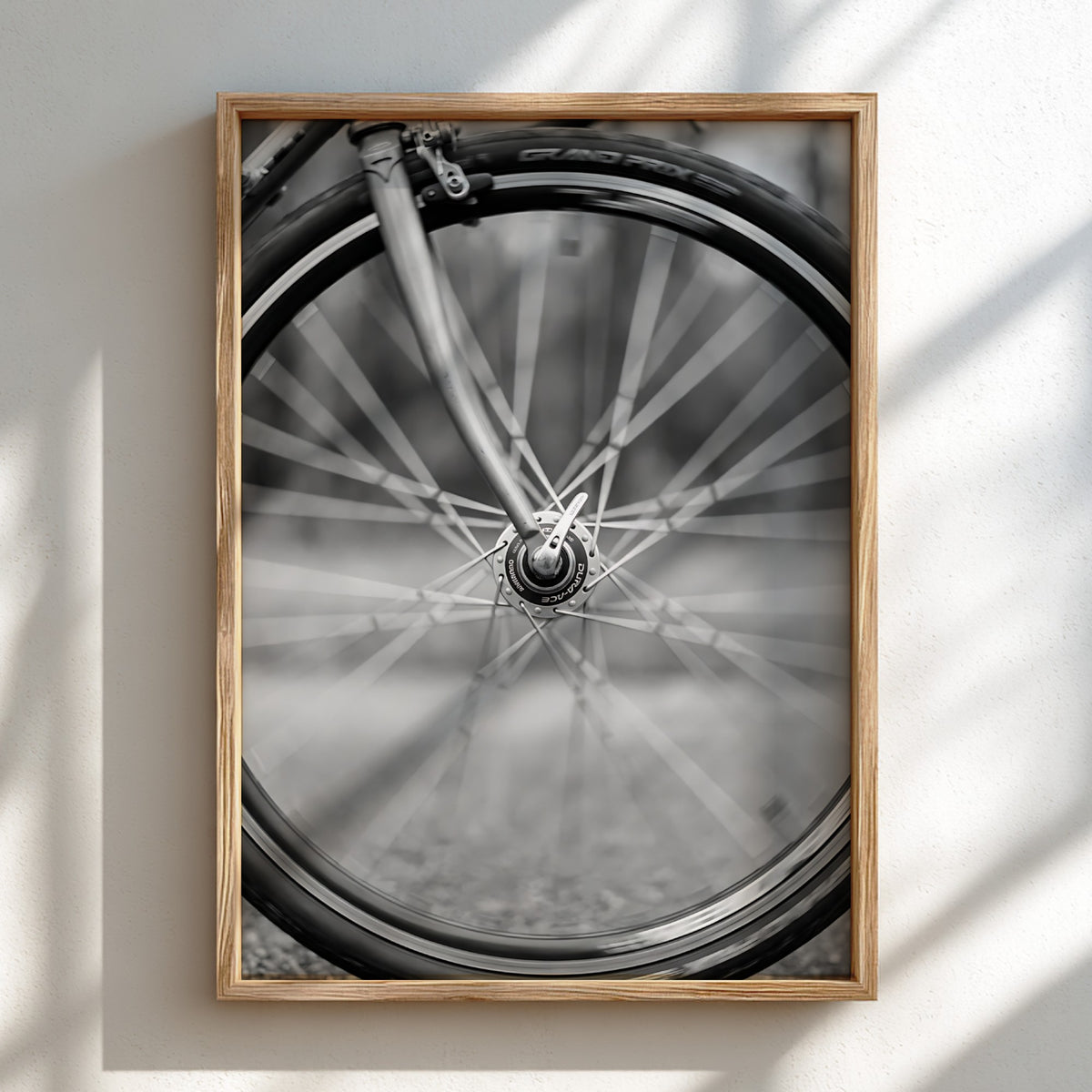 Black and white wall art of bicycle wheel in motion with blurred spokes and sharp mechanical details