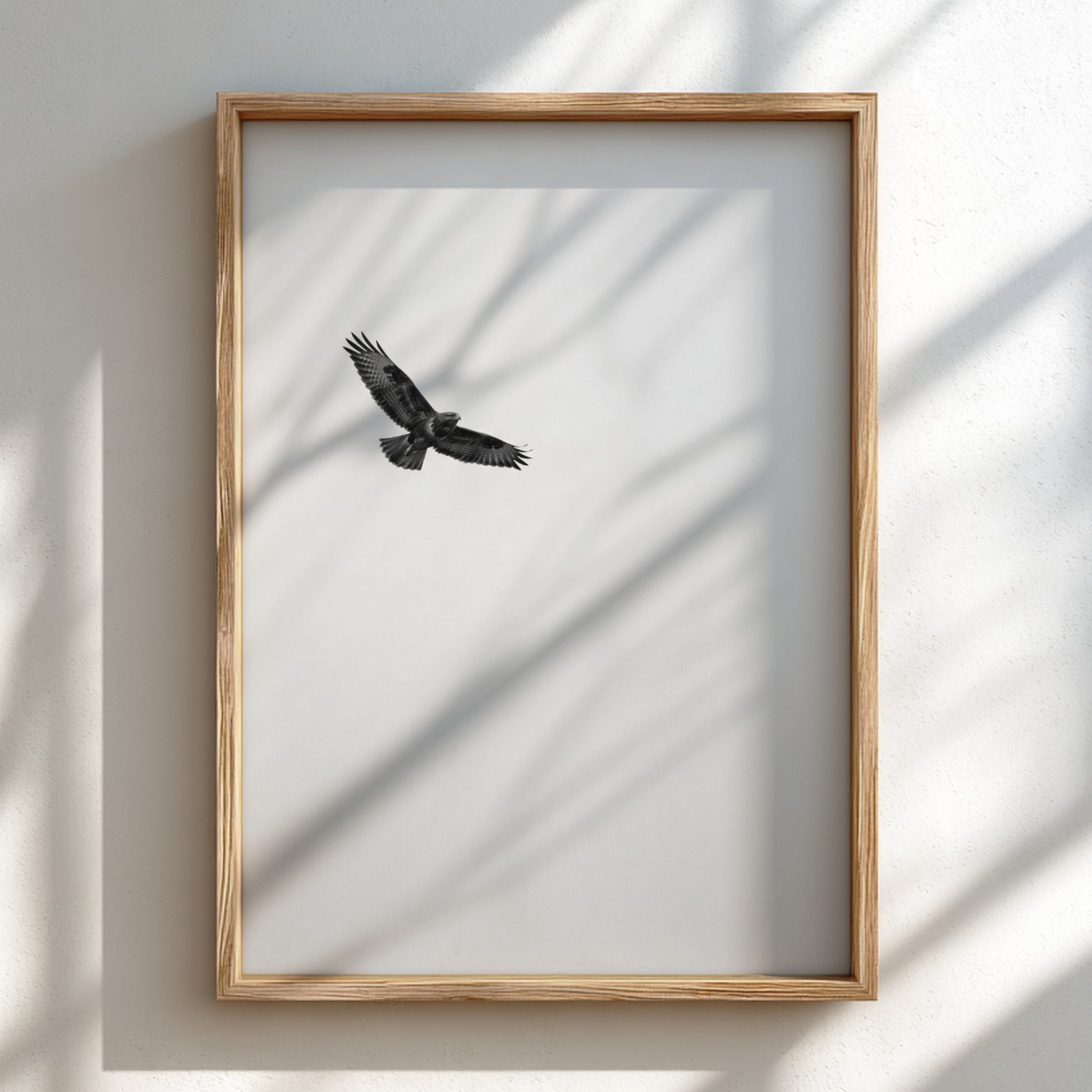 Framed wall decor featuring a black bird in flight against a pale sky with natural wood frame