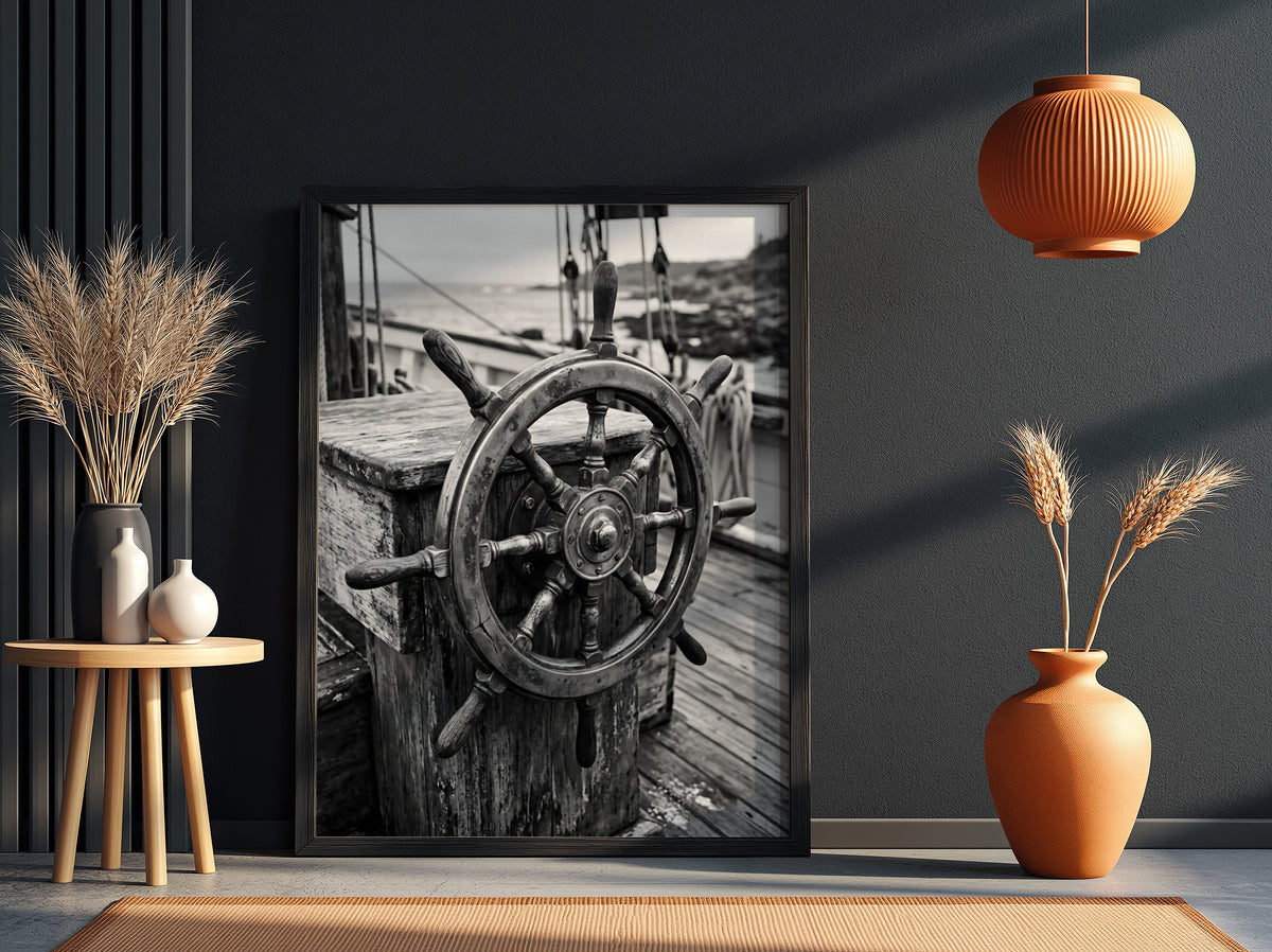 Black and white wall decor showing brass ship wheel on wooden deck with nautical ropes
