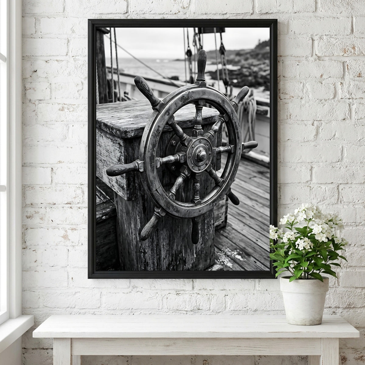 Black and white wall decor showing brass ship wheel on wooden deck with nautical ropes