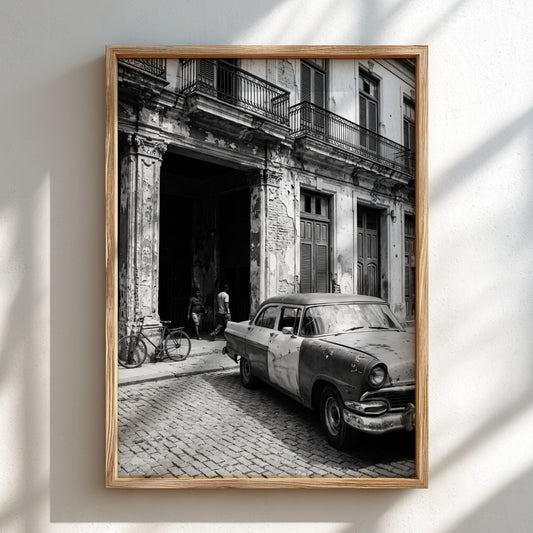 Black and white poster of vintage car parked on Havana street with colonial building and cobblestones