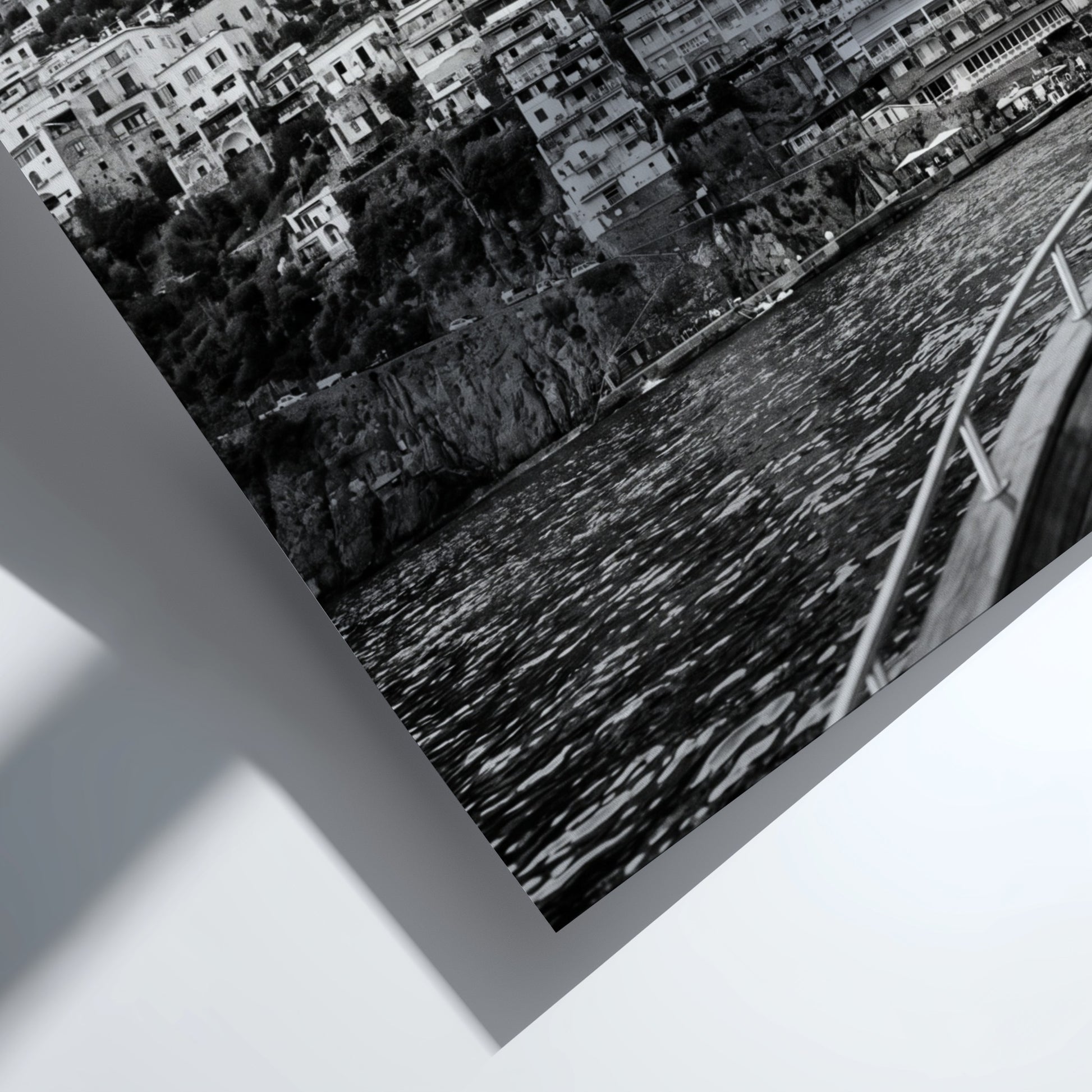 Black and white poster of cliffside village viewed from boat with coastal houses and mountain background