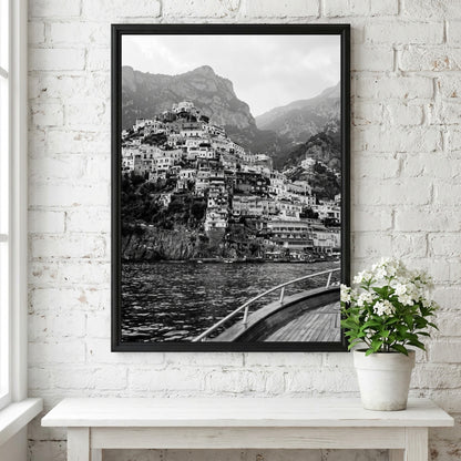 Black and white poster of cliffside village viewed from boat with coastal houses and mountain background