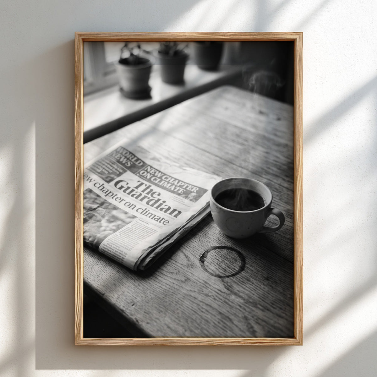 Black and white poster of coffee cup beside The Guardian newspaper on wooden table