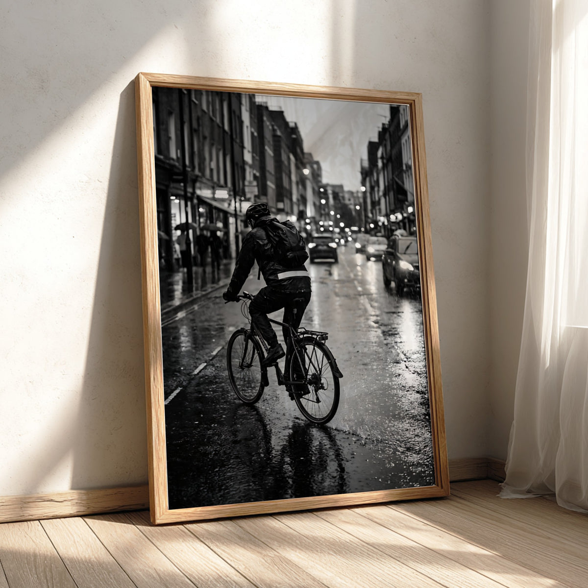 Poster of cyclist riding through rain on wet city street in black and white