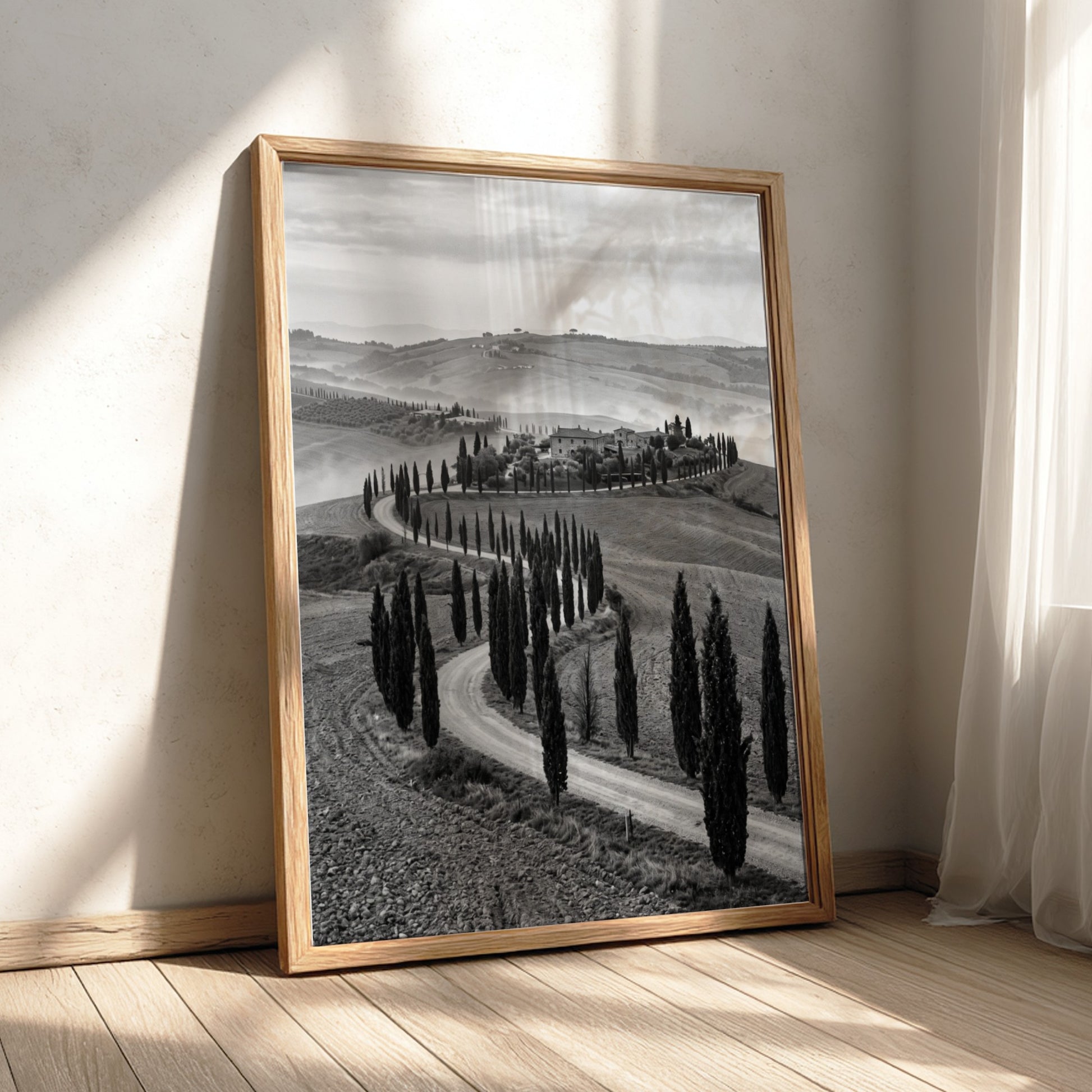 Black and white wall decor featuring tall cypress trees lining winding road on rolling hills