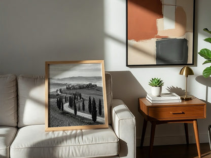 Black and white wall decor featuring tall cypress trees lining winding road on rolling hills