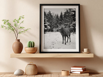 black and white nature wall decor showing deer standing in snowy forest clearing with pine trees