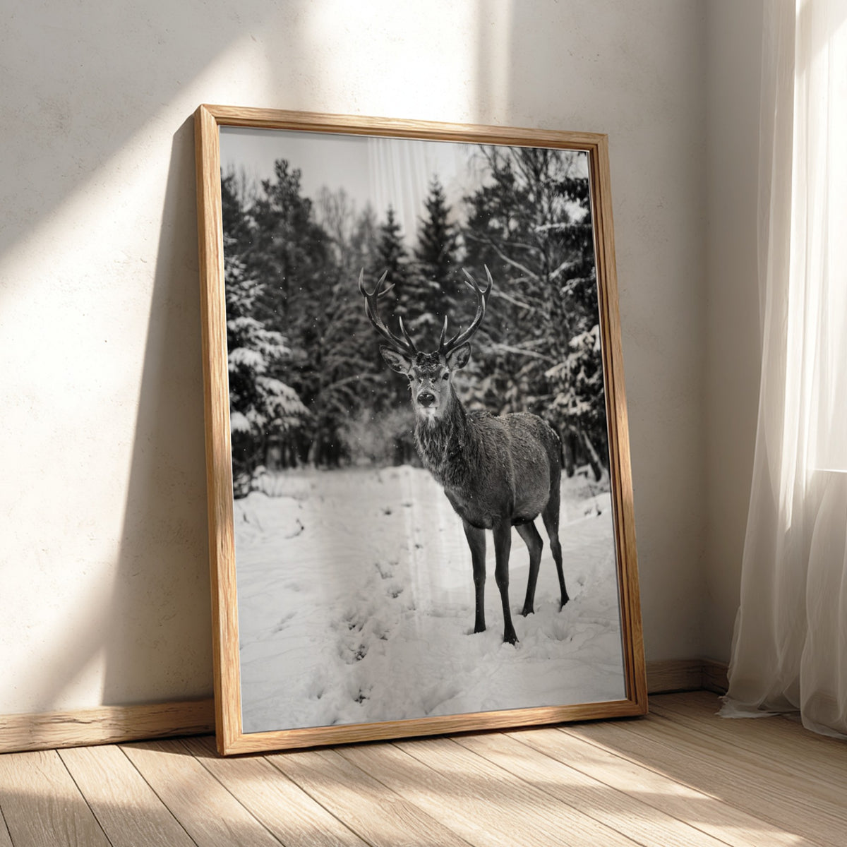black and white nature wall decor showing deer standing in snowy forest clearing with pine trees