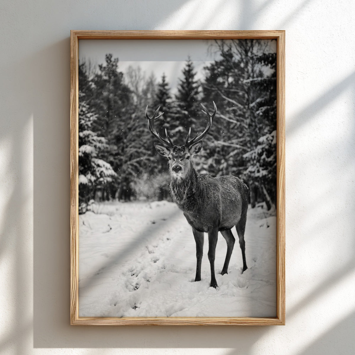 black and white nature wall decor showing deer standing in snowy forest clearing with pine trees