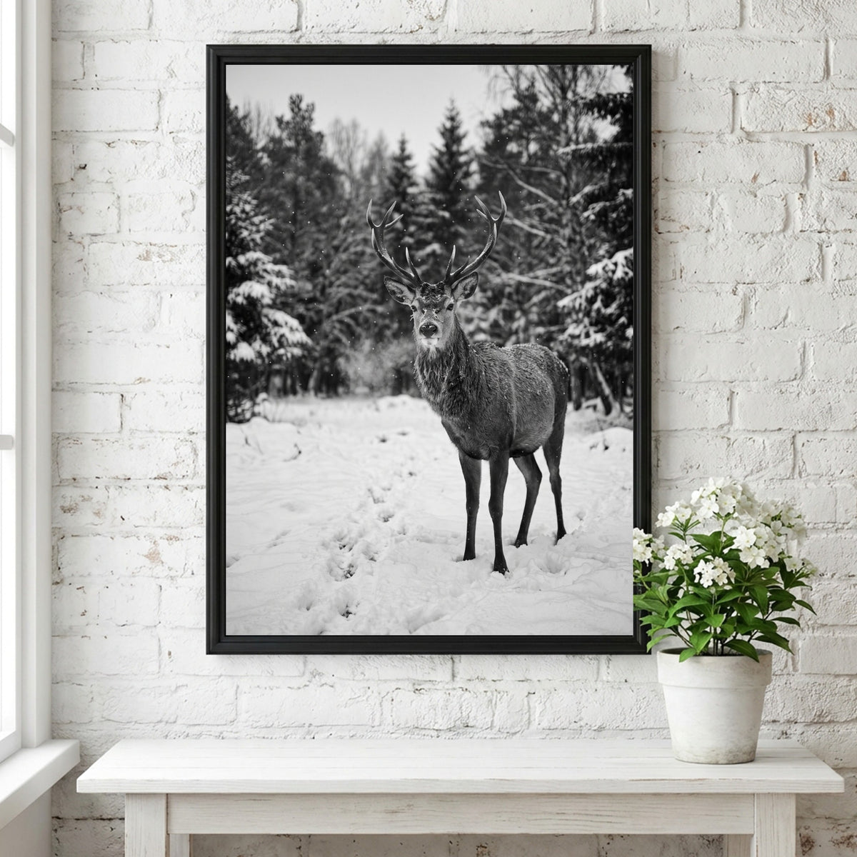 black and white nature wall decor showing deer standing in snowy forest clearing with pine trees