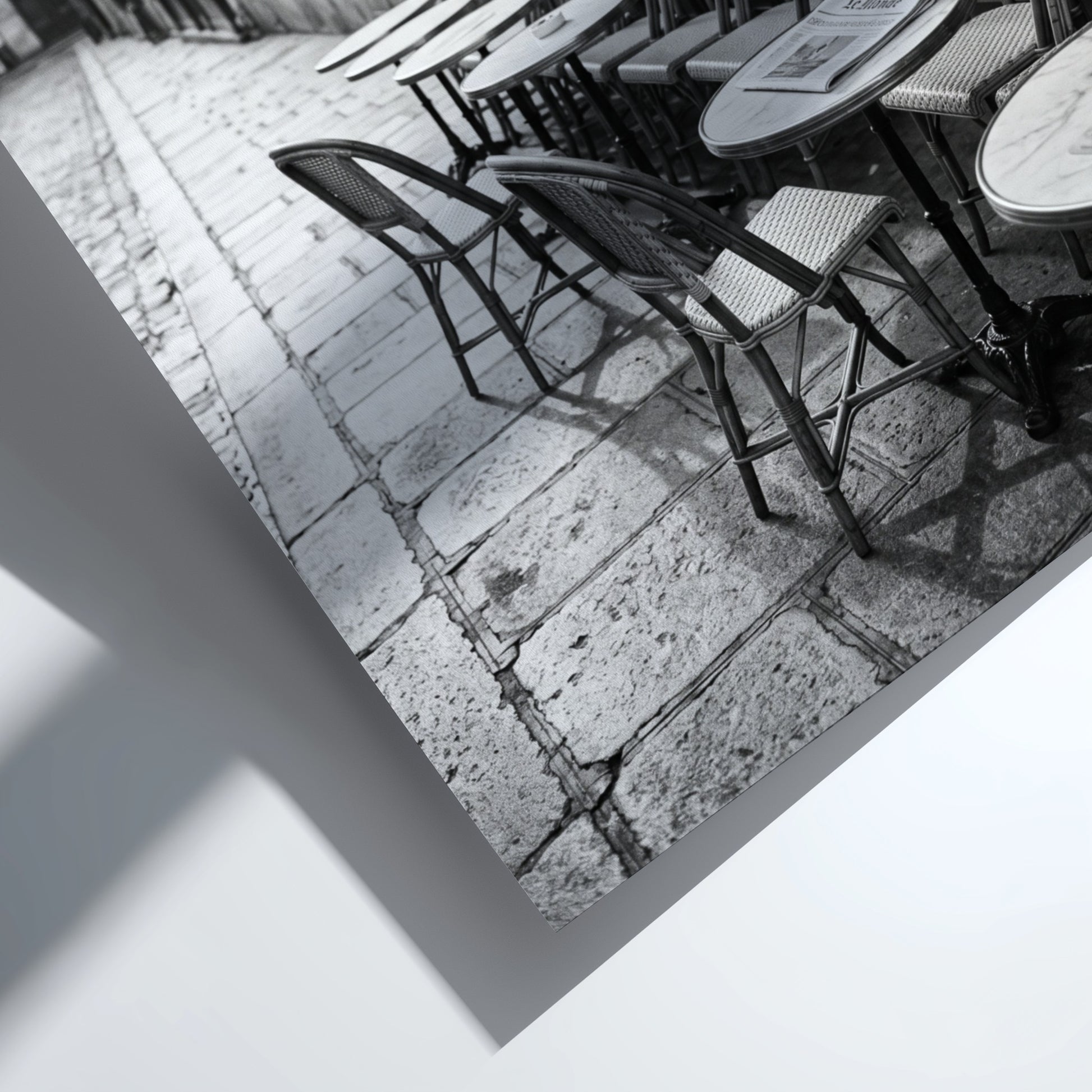Black and white wall decor featuring empty Parisian cafe terrace with chairs and tables on cobblestone street