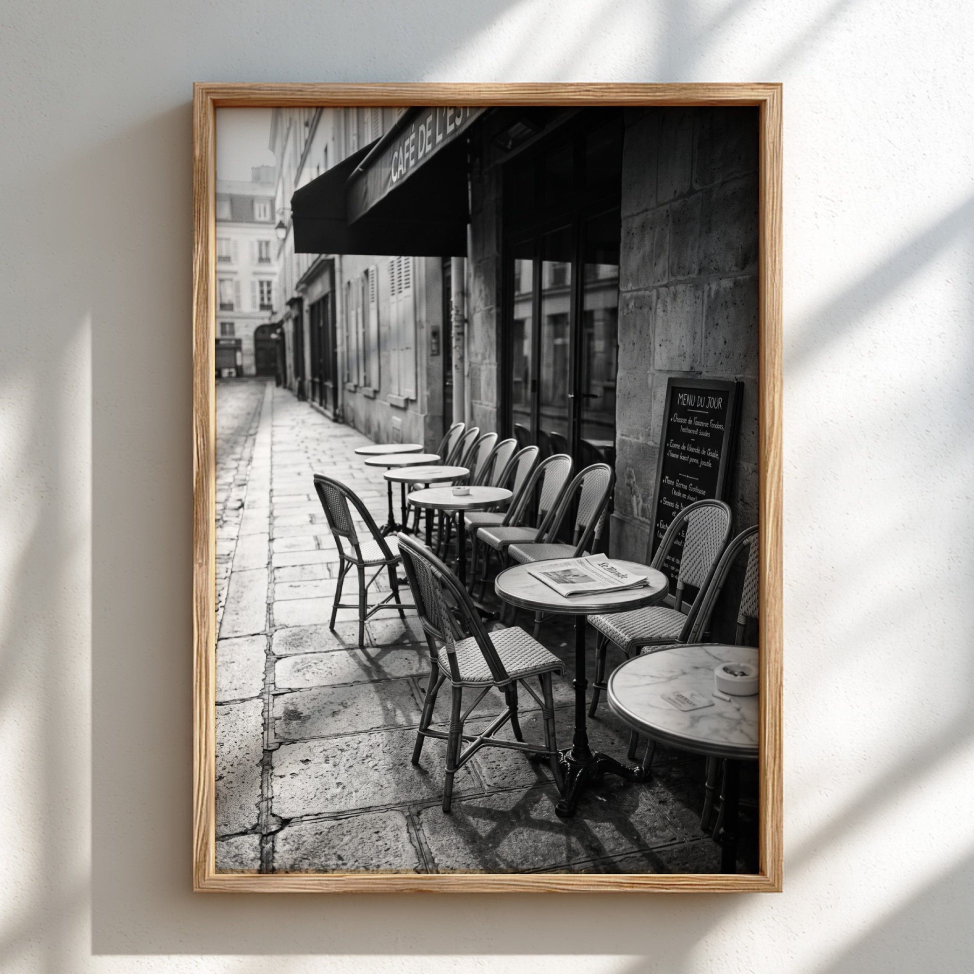 Black and white wall decor featuring empty Parisian cafe terrace with chairs and tables on cobblestone street
