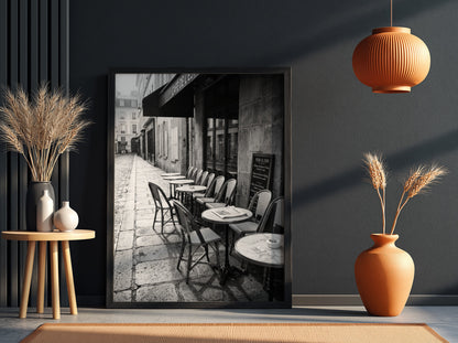 Black and white wall decor featuring empty Parisian cafe terrace with chairs and tables on cobblestone street