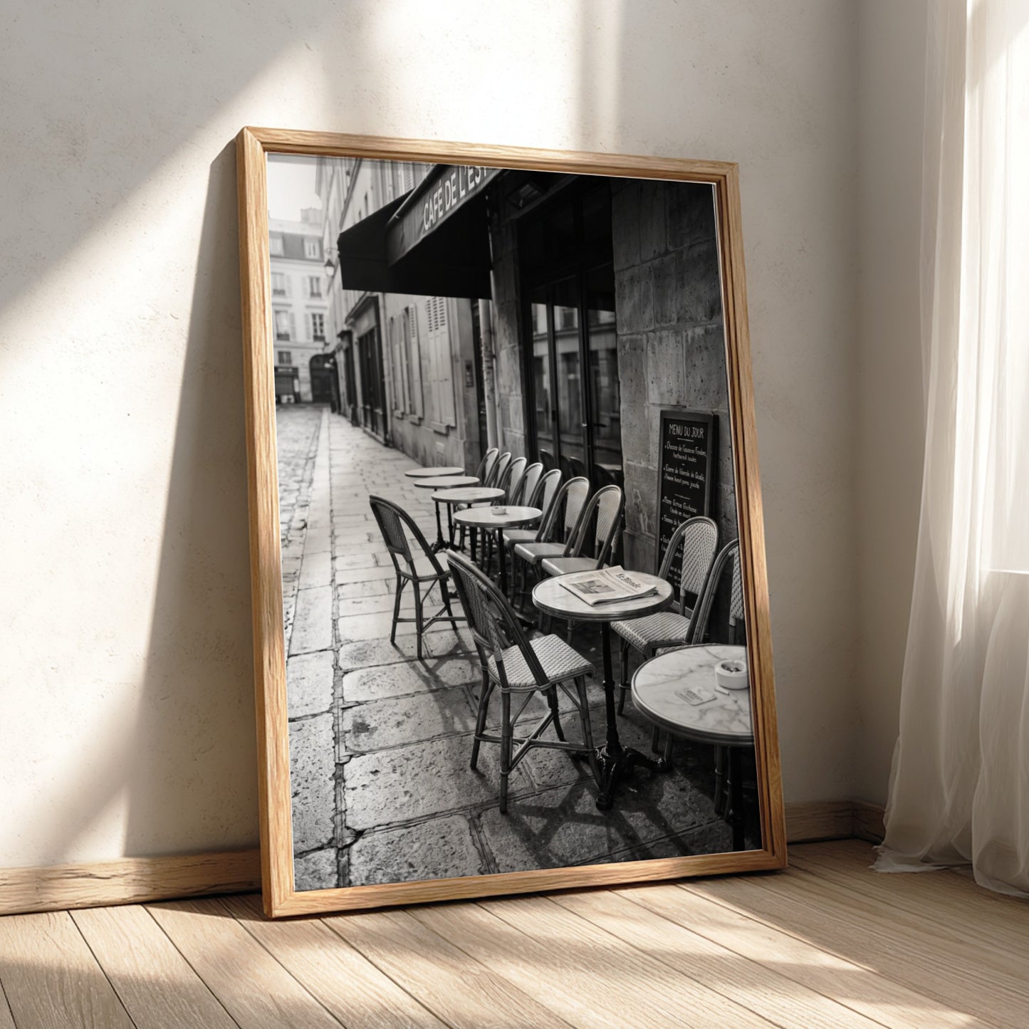 Black and white wall decor featuring empty Parisian cafe terrace with chairs and tables on cobblestone street
