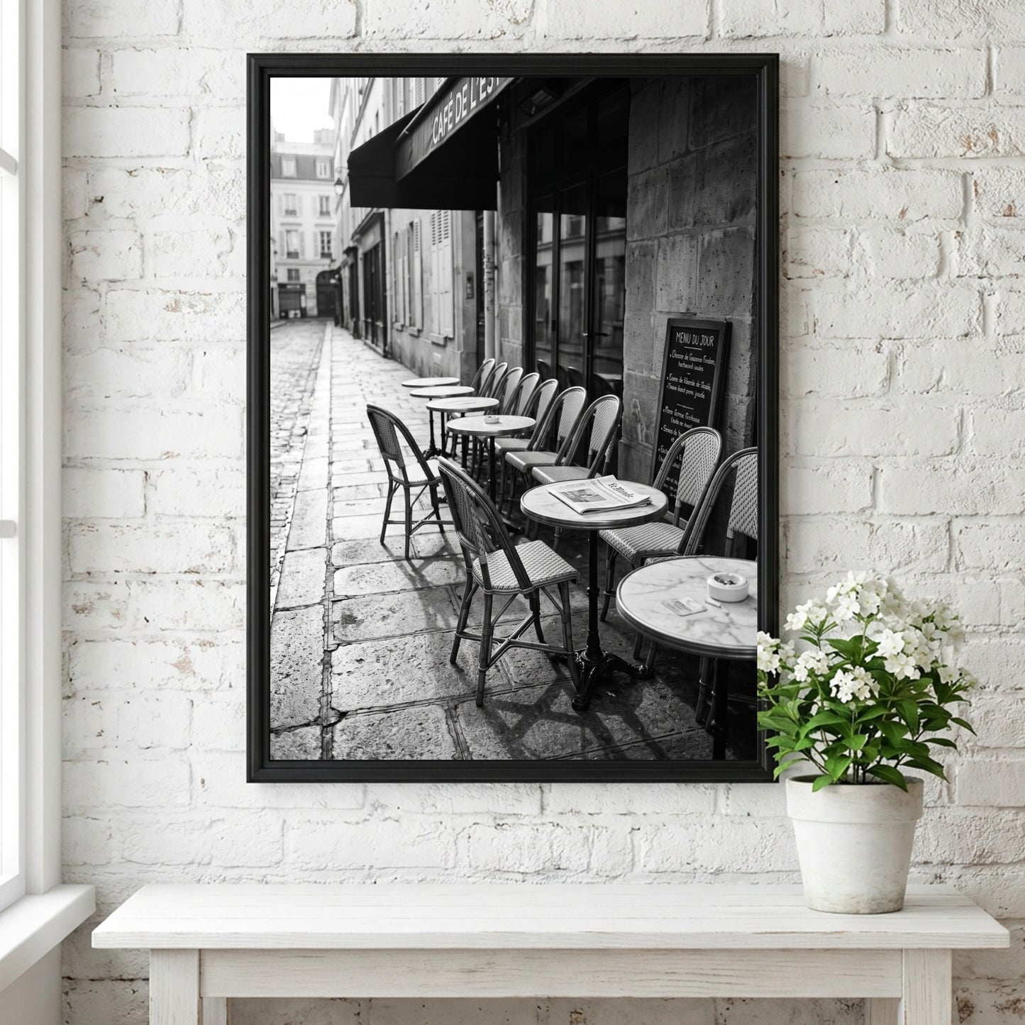 Black and white wall decor featuring empty Parisian cafe terrace with chairs and tables on cobblestone street