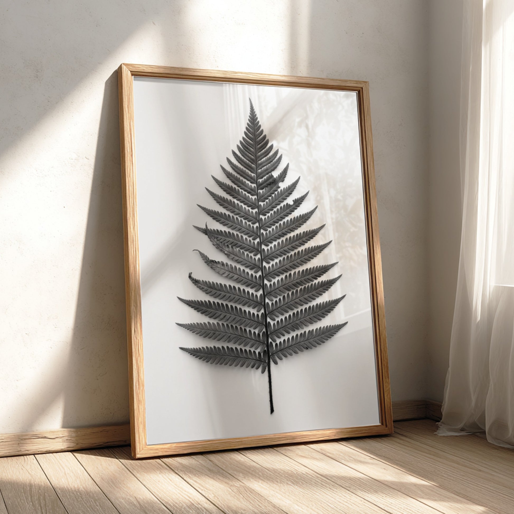 Botanical poster showing a detailed monochrome fern frond laid flat with natural wood frame and soft shadows