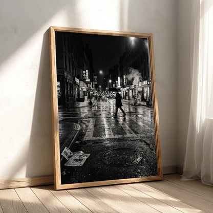Black and white urban wall decor showing figure crossing wet street at night with reflective asphalt and