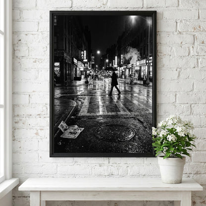 Black and white urban wall decor showing figure crossing wet street at night with reflective asphalt and