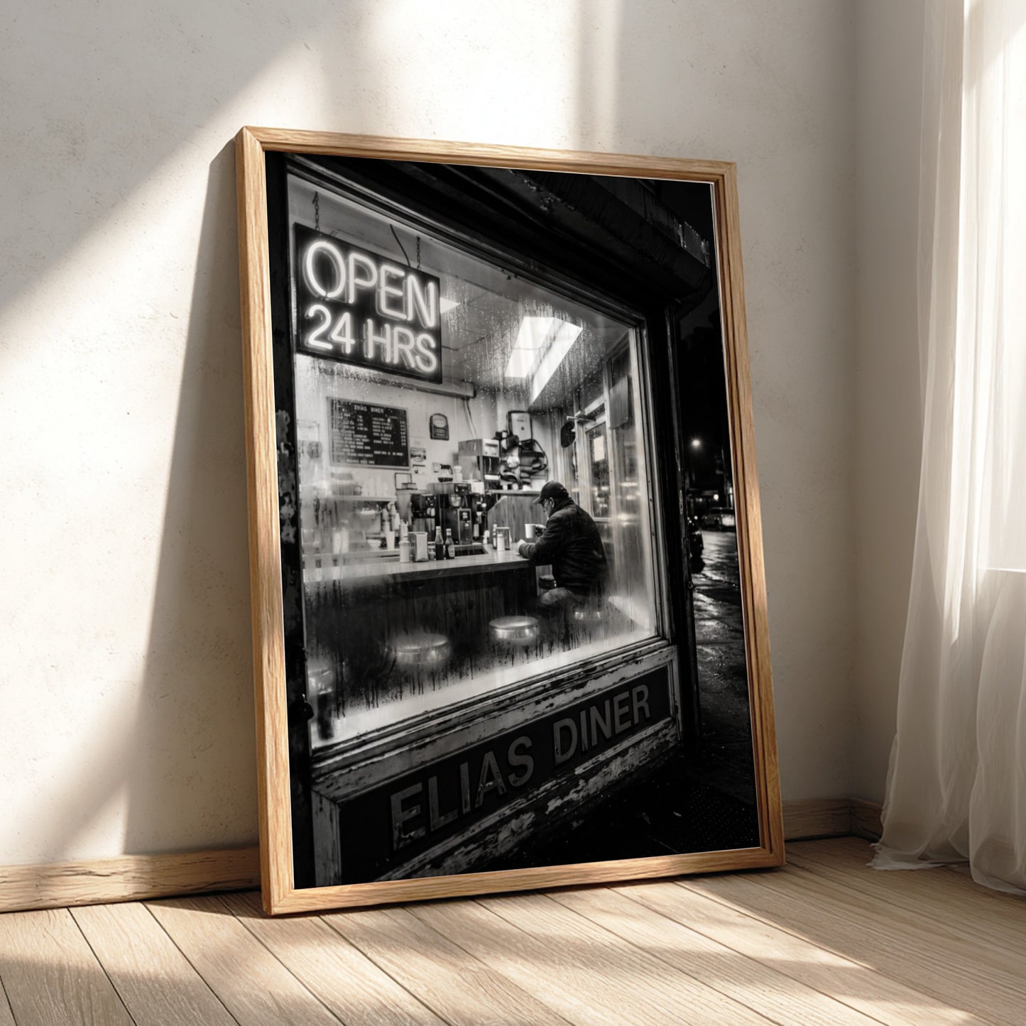 Poster of black and white diner interior with neon open 24 hrs sign and lone figure sitting
