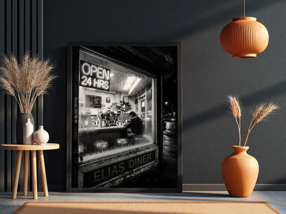 Poster of black and white diner interior with neon open 24 hrs sign and lone figure sitting