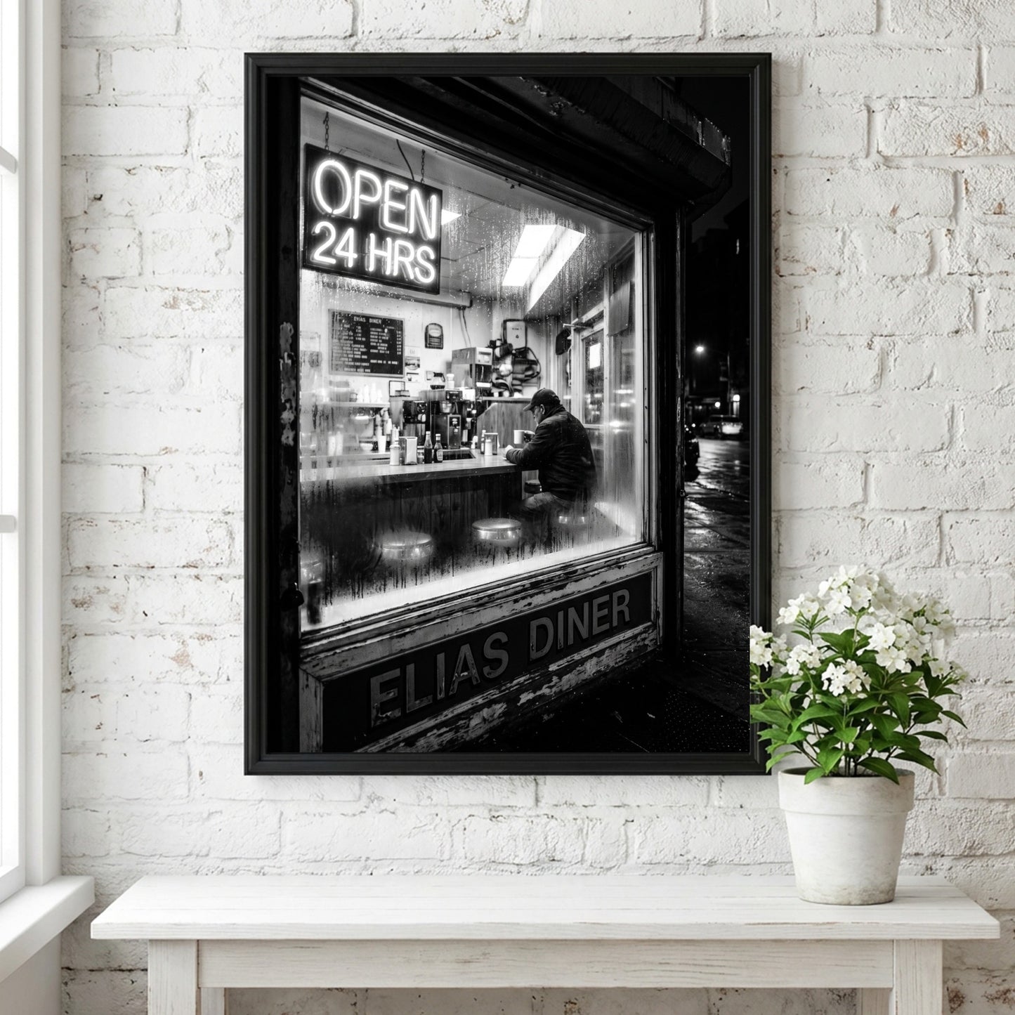 Poster of black and white diner interior with neon open 24 hrs sign and lone figure sitting