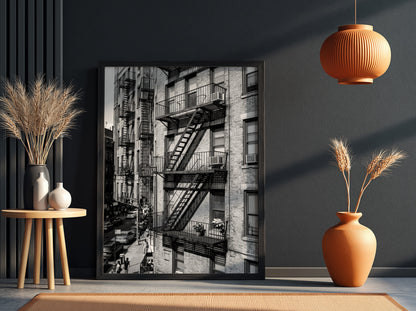 black and white wall decor featuring fire escape on brick tenement building with urban street below