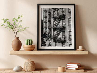 black and white wall decor featuring fire escape on brick tenement building with urban street below