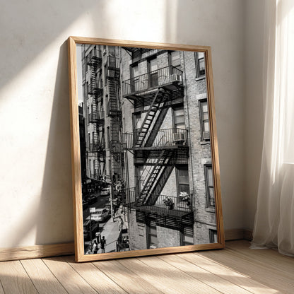 black and white wall decor featuring fire escape on brick tenement building with urban street below
