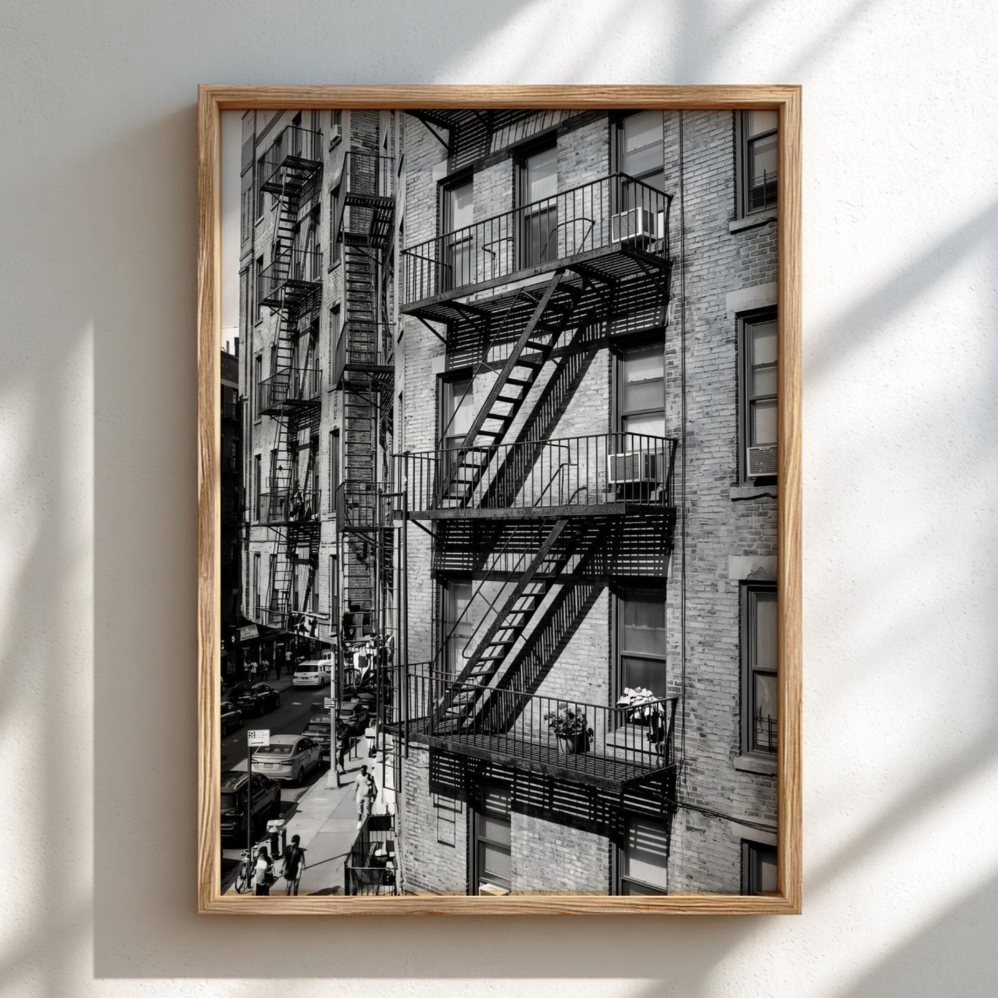 black and white wall decor featuring fire escape on brick tenement building with urban street below