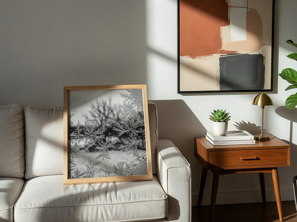 Poster of frost patterns on window with blurred winter trees background in grayscale