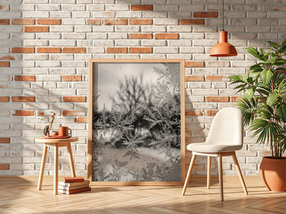 Poster of frost patterns on window with blurred winter trees background in grayscale